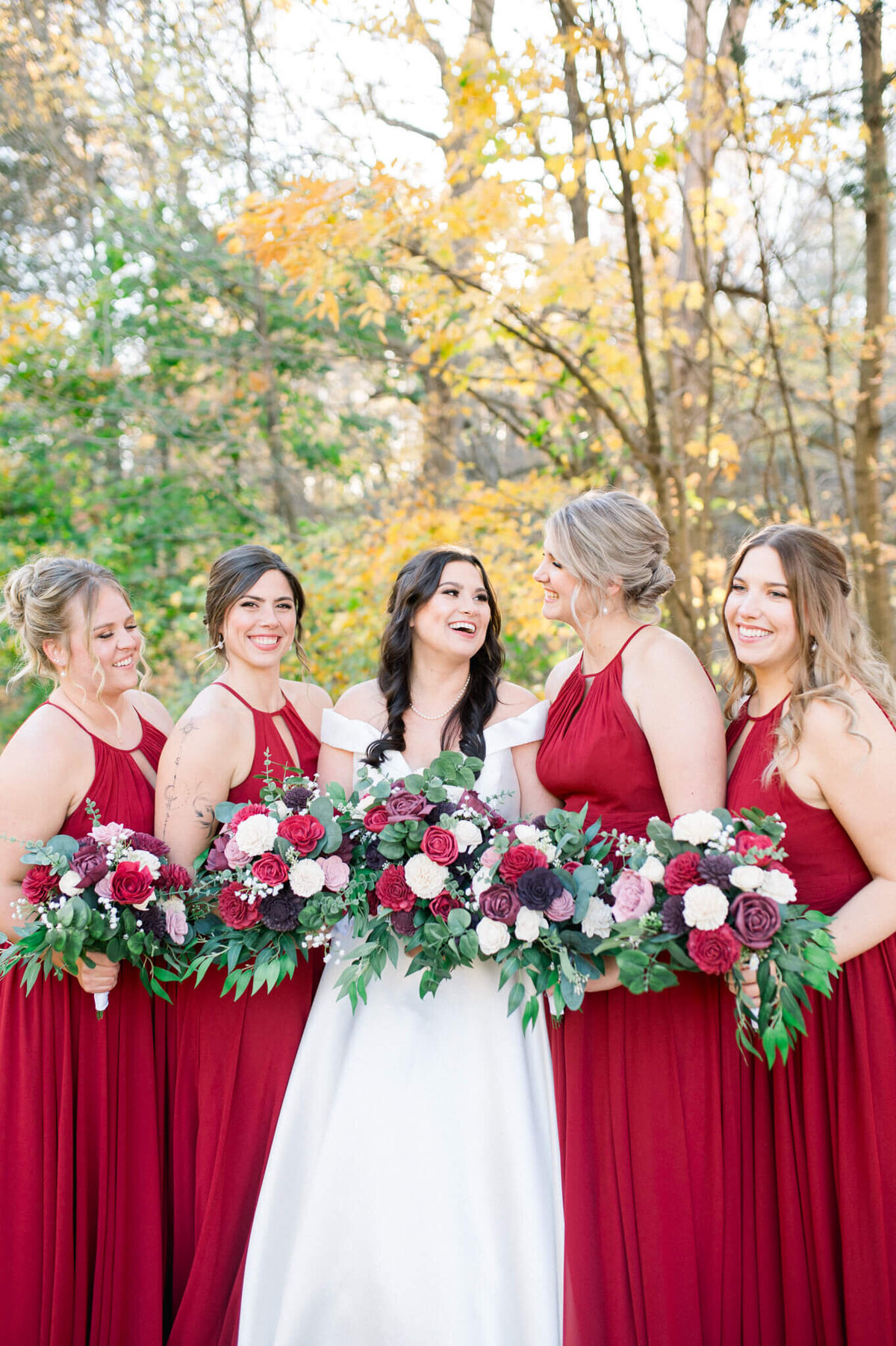 Niagara wedding photography of bridesmaids in red around bride laughing.