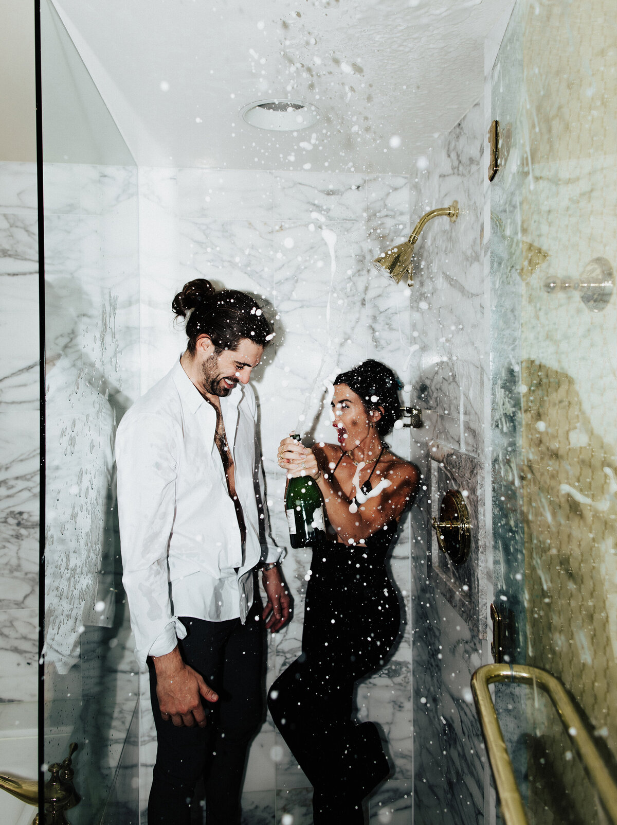 engaged-couple-popping-champagne-in-hotel-shower