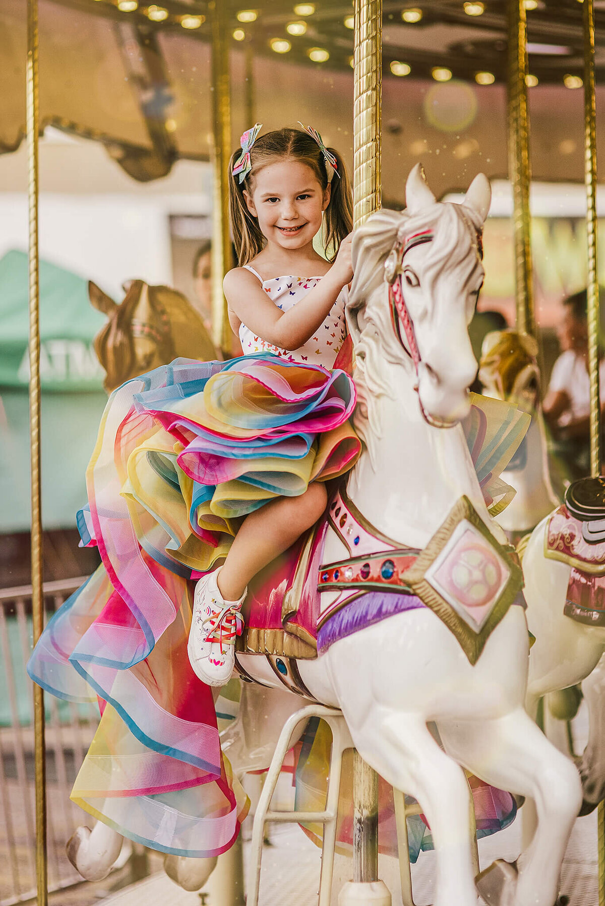 Girl in a rainbow dress and pigtails on a carousel horse near Annapolis Maryland