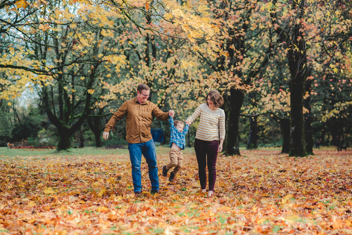 family of three walking in leaves