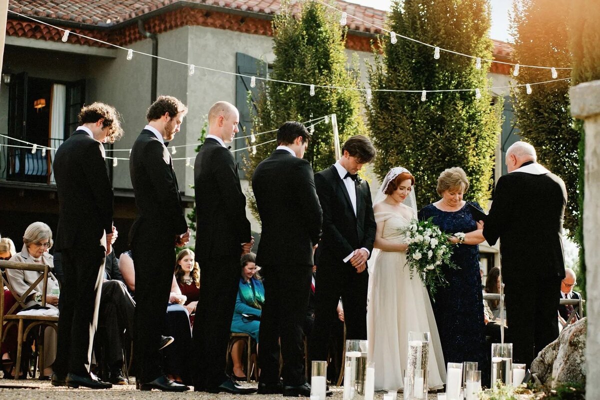 A bride and groom with their wedding parties standing up during their wedding.