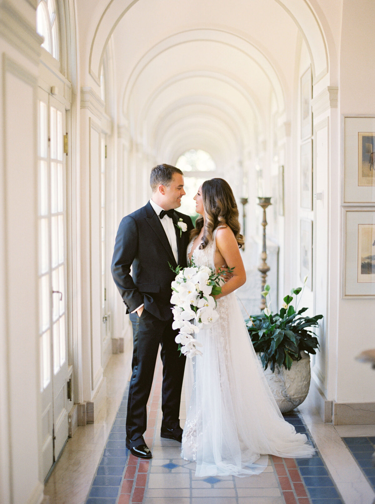 Bride and groom embrace in arched walkway
