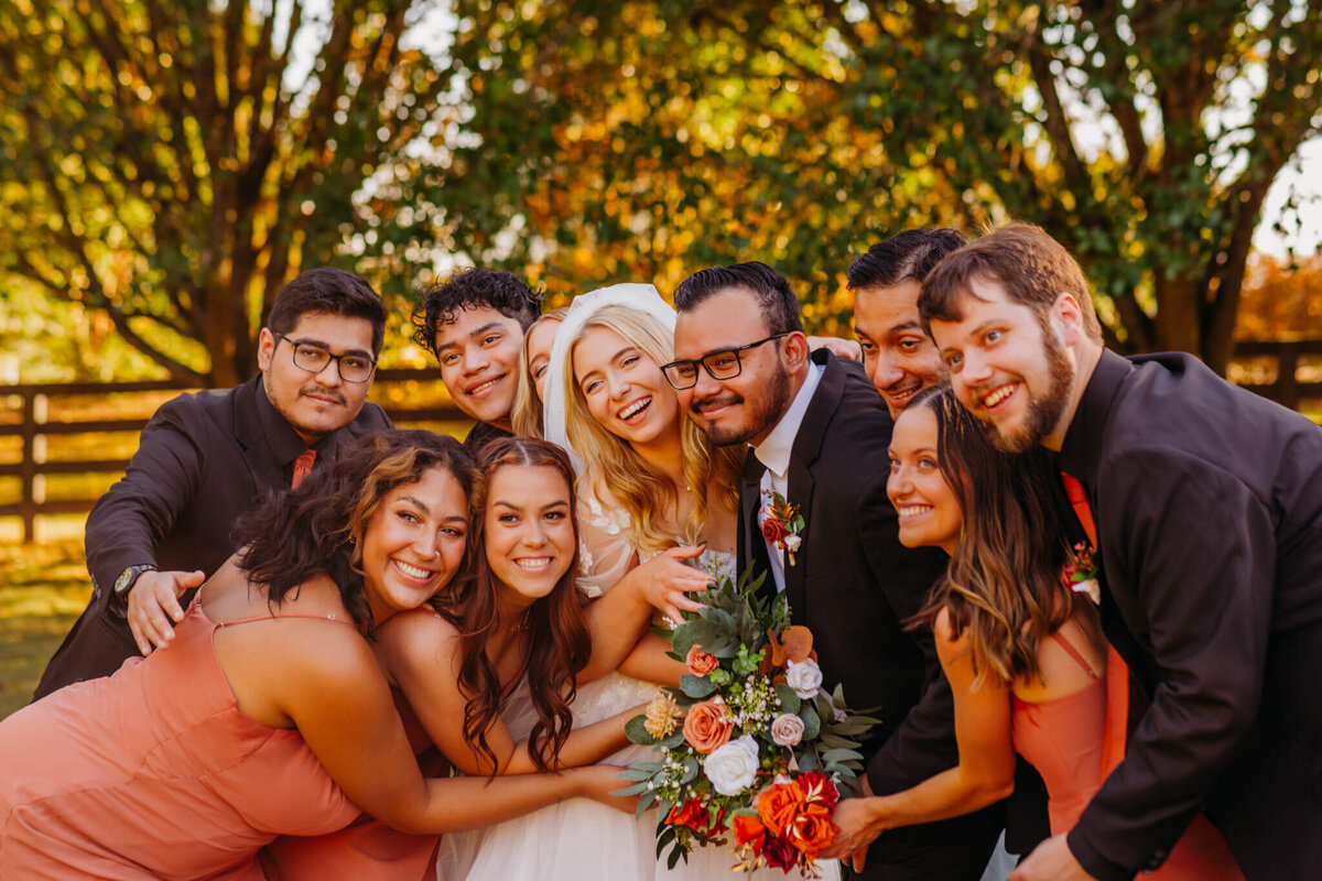 Photo of a bride and groom in a group hug with their wedding party