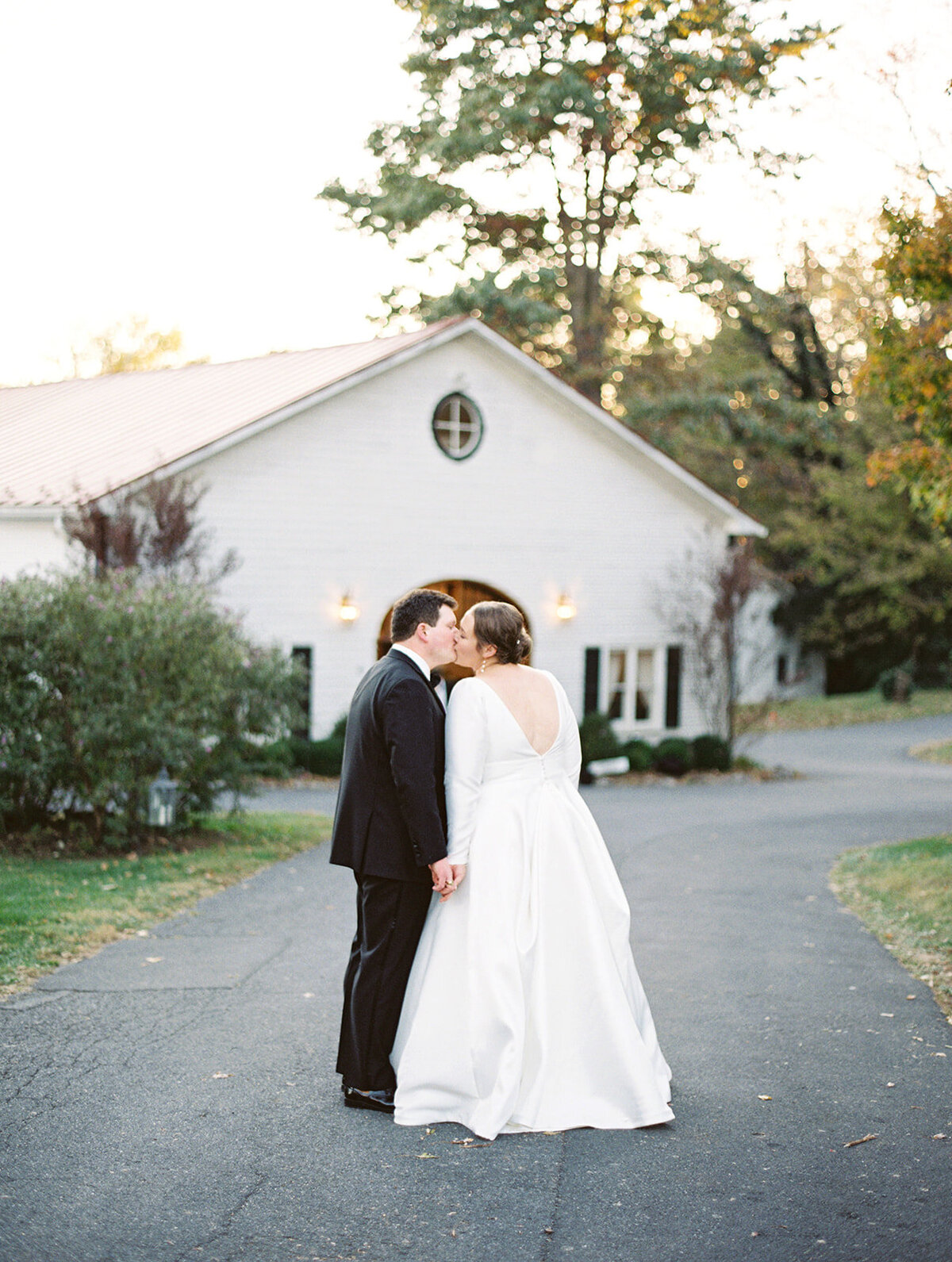 couple kiss as they are walking towards their reception at rosemont manor carriage house.