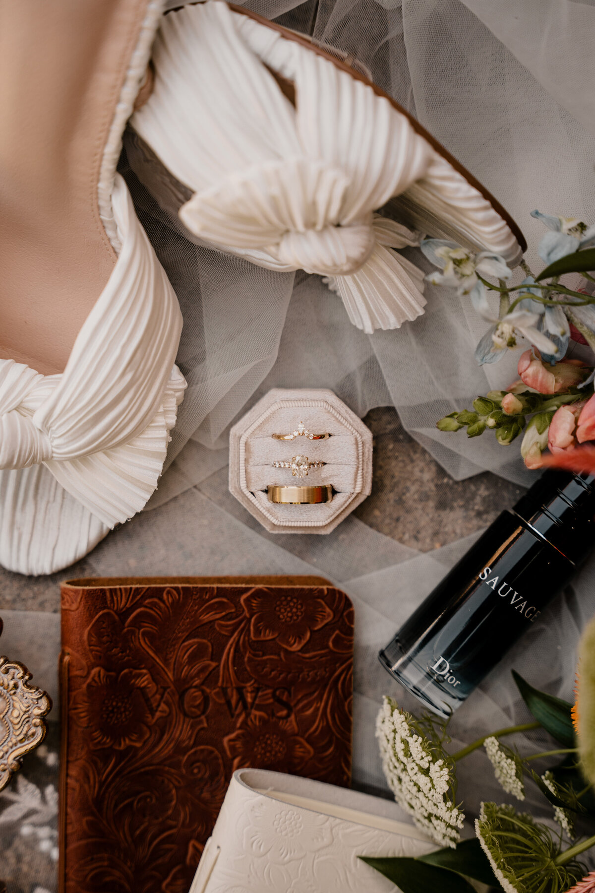 White wedding heels, wedding rings, and other details are laid atop the wedding veil.