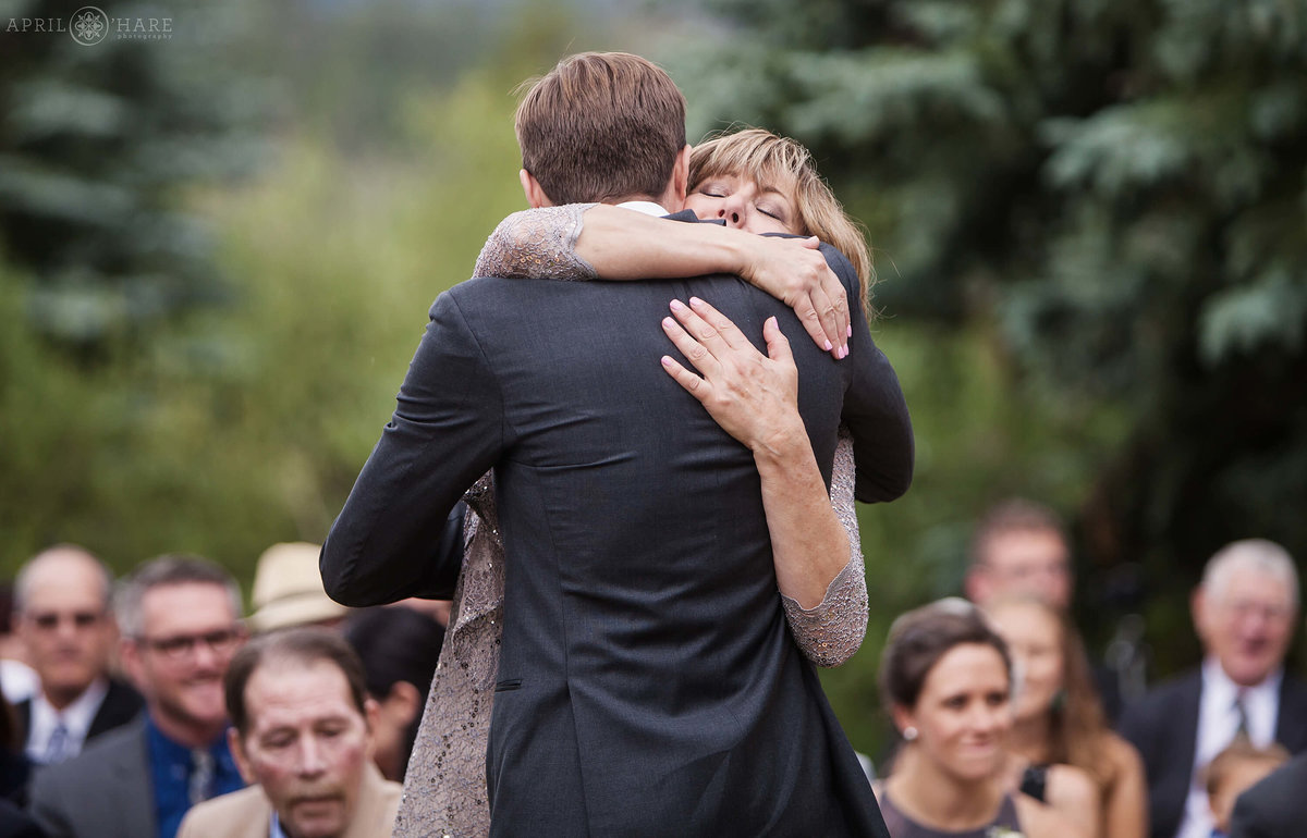 Mom hugs her son at outdoor Colorado mountain wedding at Wedgewood Mountain View Ranch in Pine
