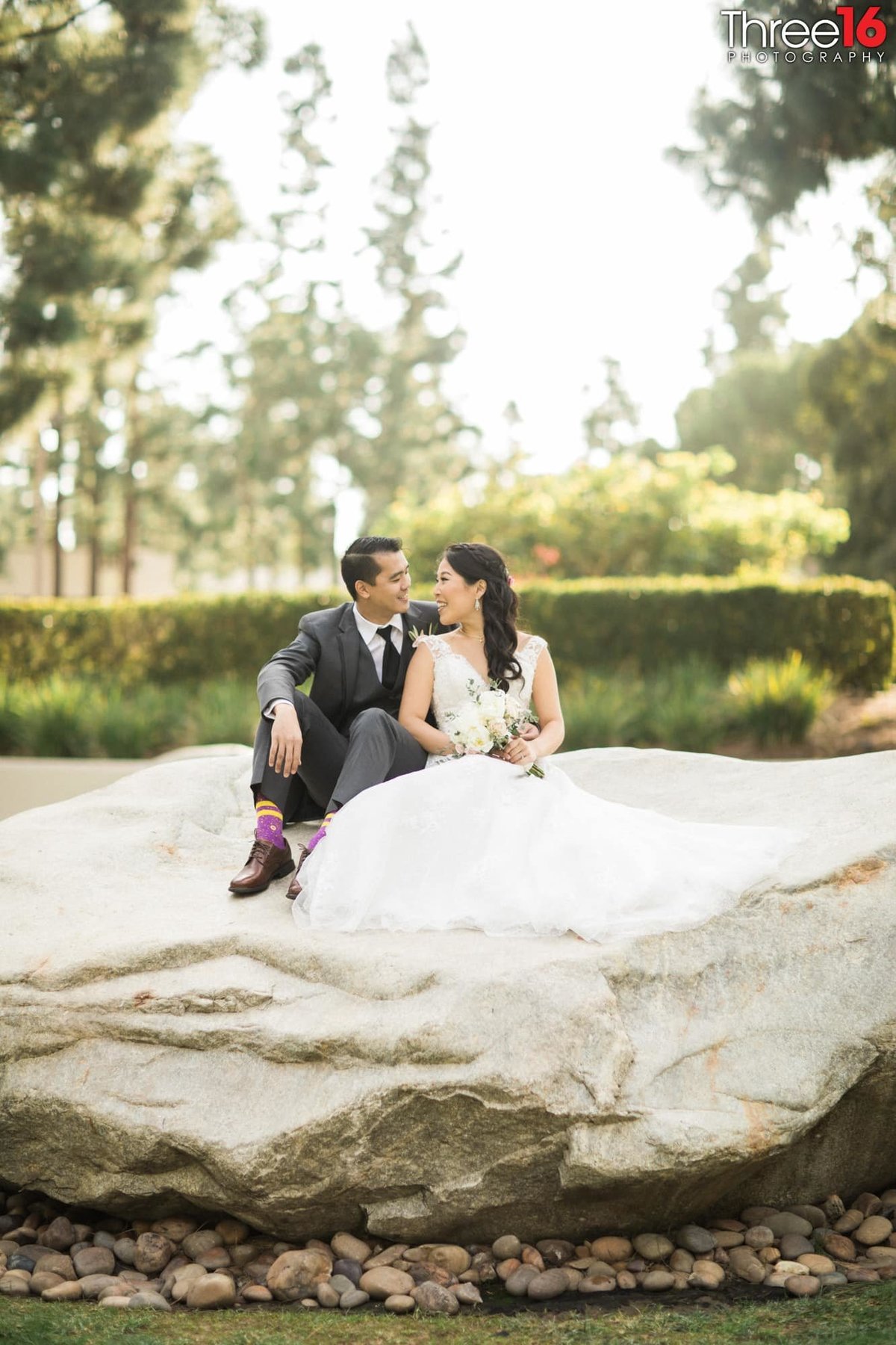 Bride and Groom gaze at each other while sitting on a rock together