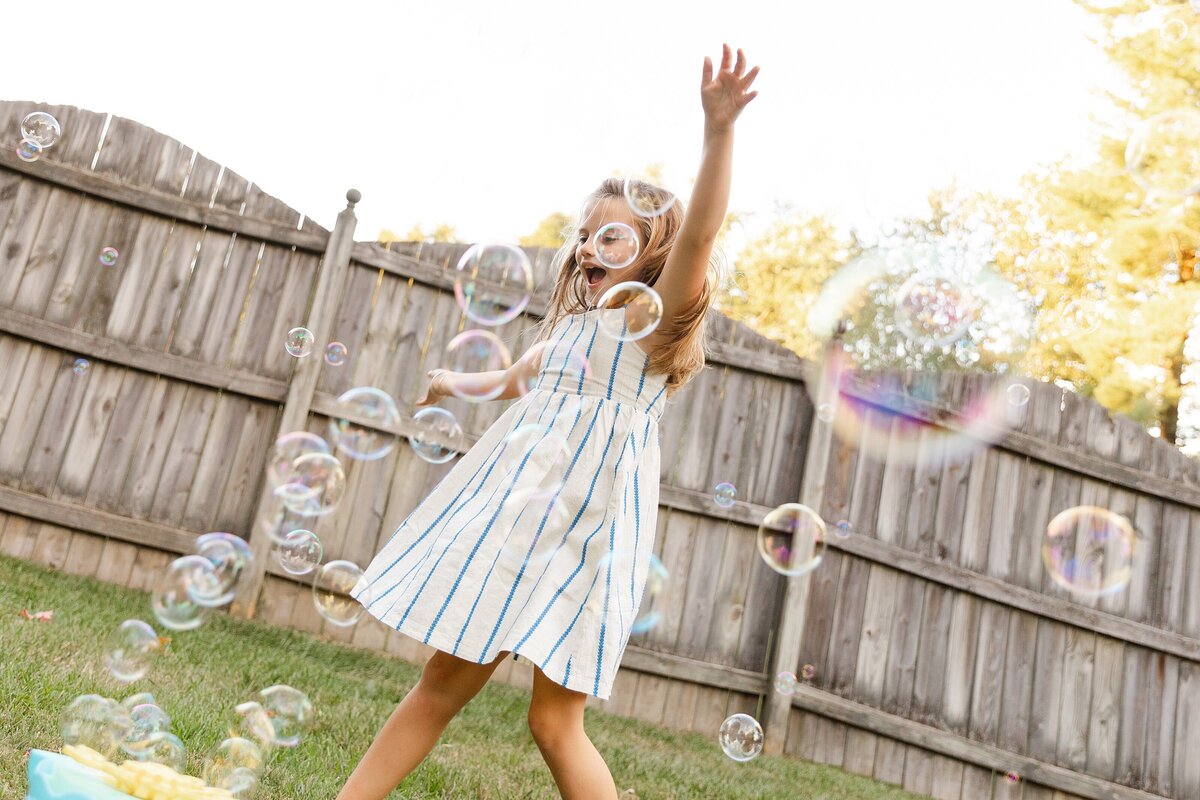 A little girl dancing in bubbles.