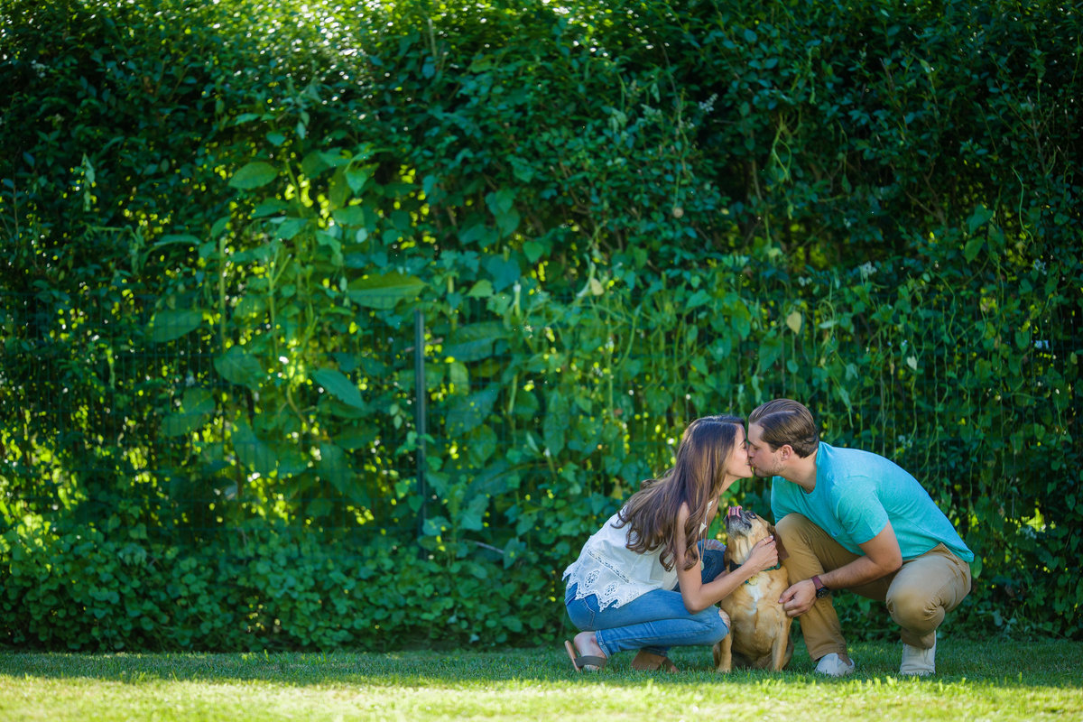 couple with dog sharing a kiss