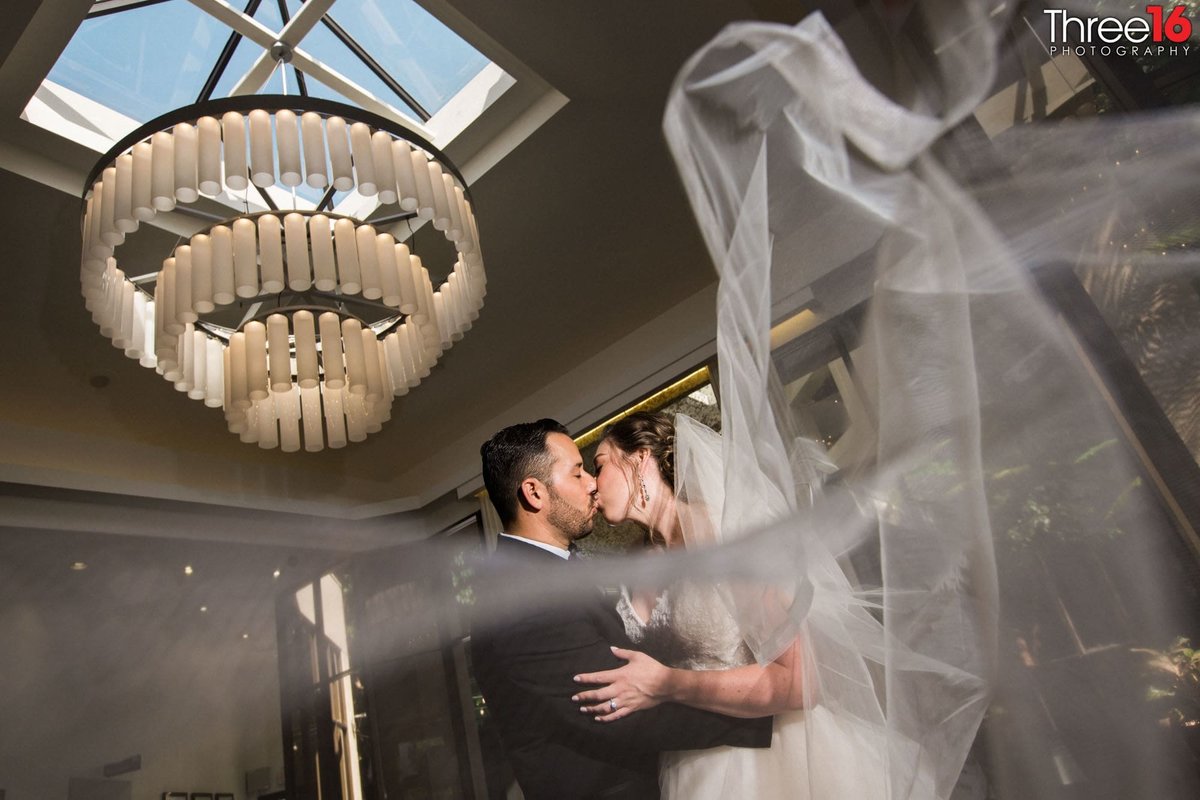 Bride and Groom share a kiss under the chandelier