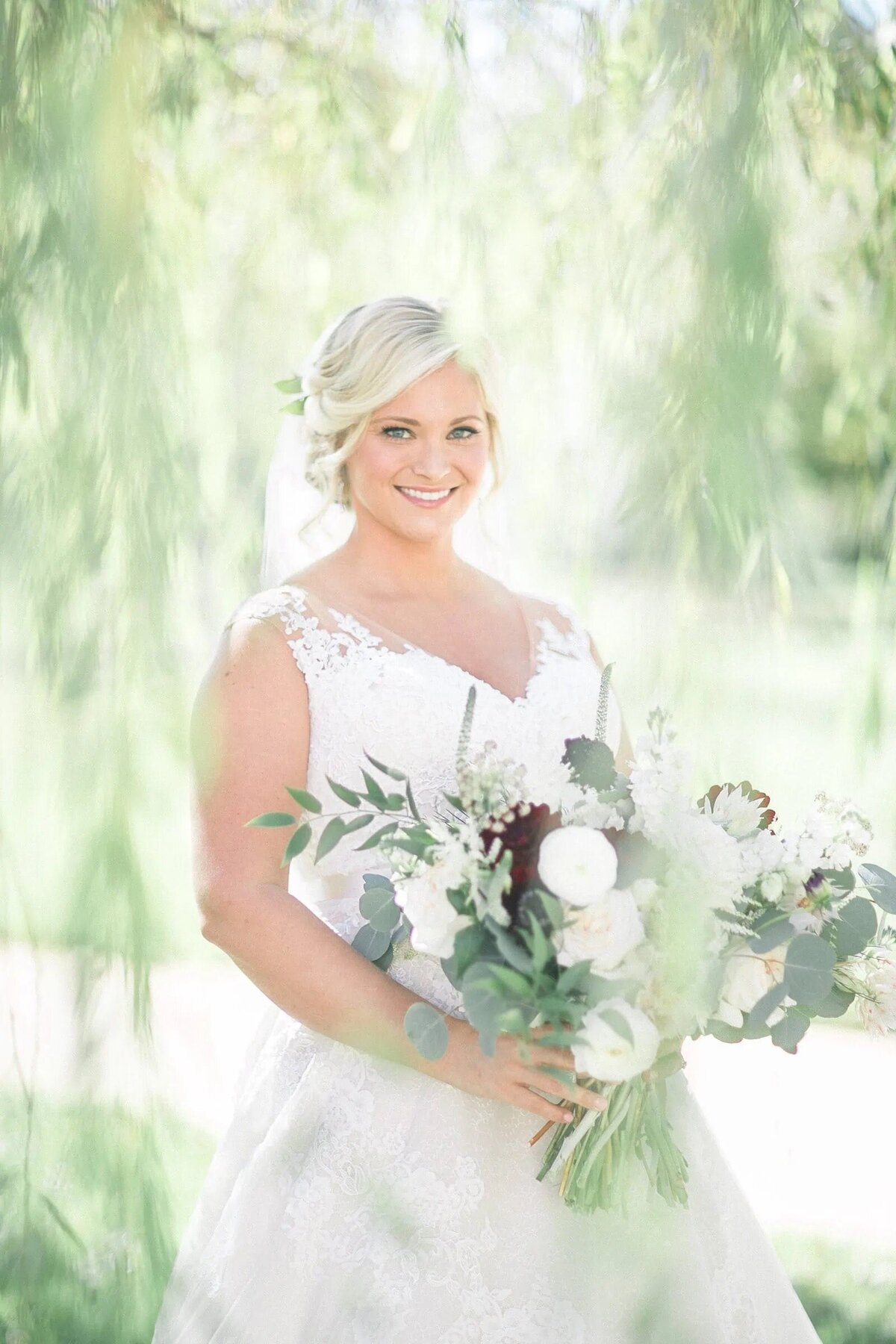 A bride smiling and holding a bouquet of flowers