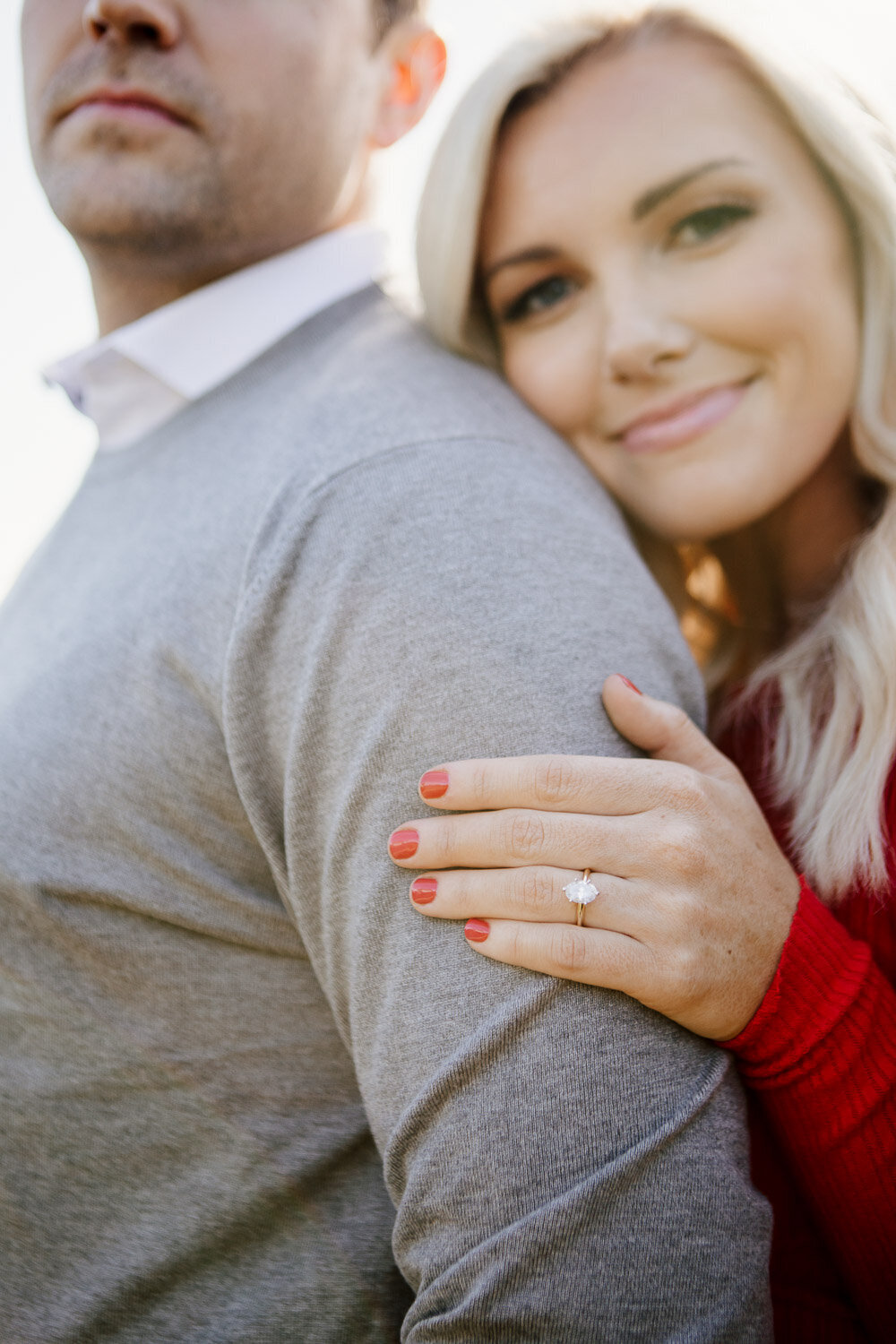 Couple embracing and focusing on engagement ring on woman's hand