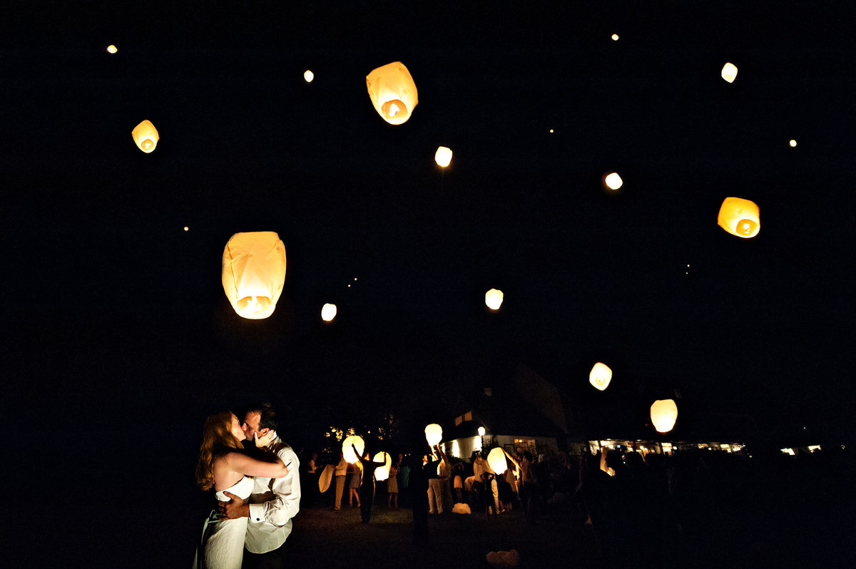 Wedding guests light paper lanterns  at the end of the wedding at Pheasant Run Farm.