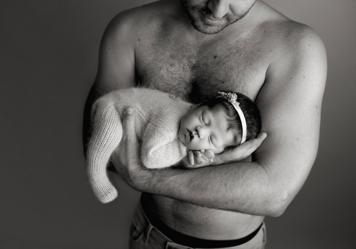 shirtless dad holding newborn daughter for studio photos in denver