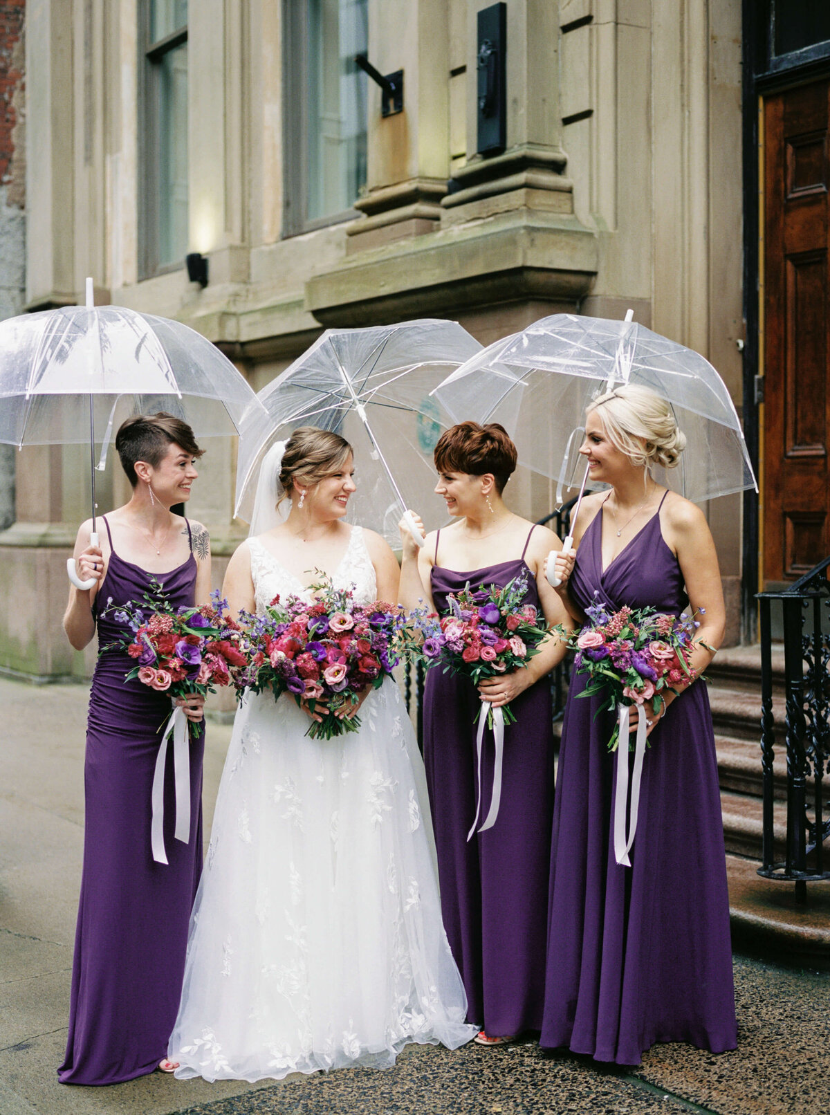 Bride with bridesmaids in purple dresses standing outside the Halifax Club in Nova Scotia