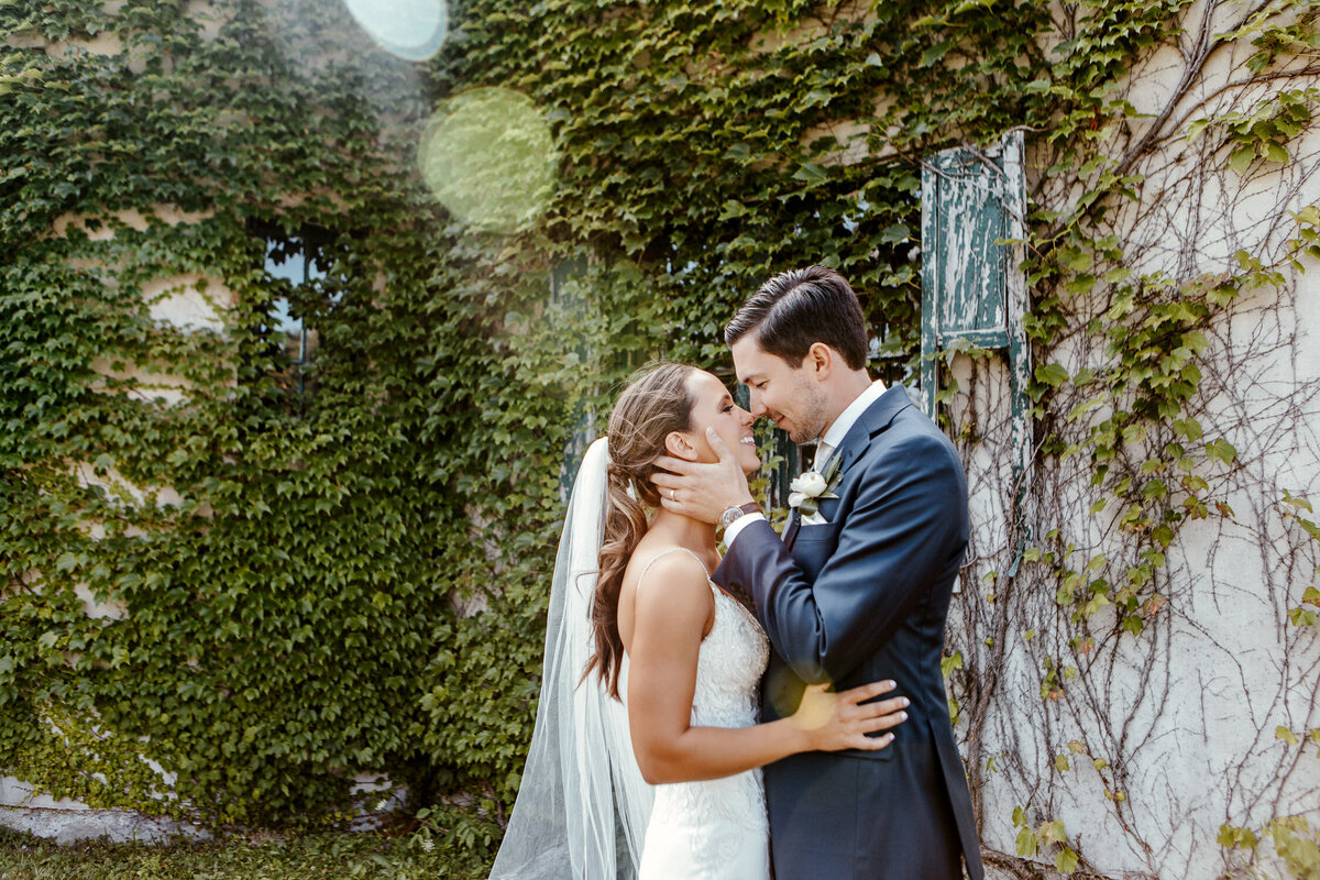 Bride & Groom kissing in Knox Farm, New York with foliage building wall