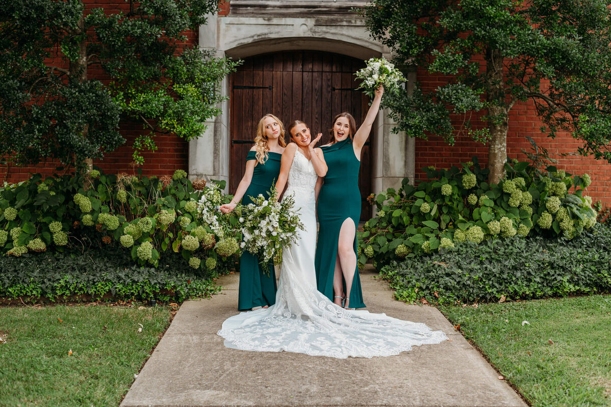 photo of bridesmaids cheering while standing on a pathway with hydrangea bushes