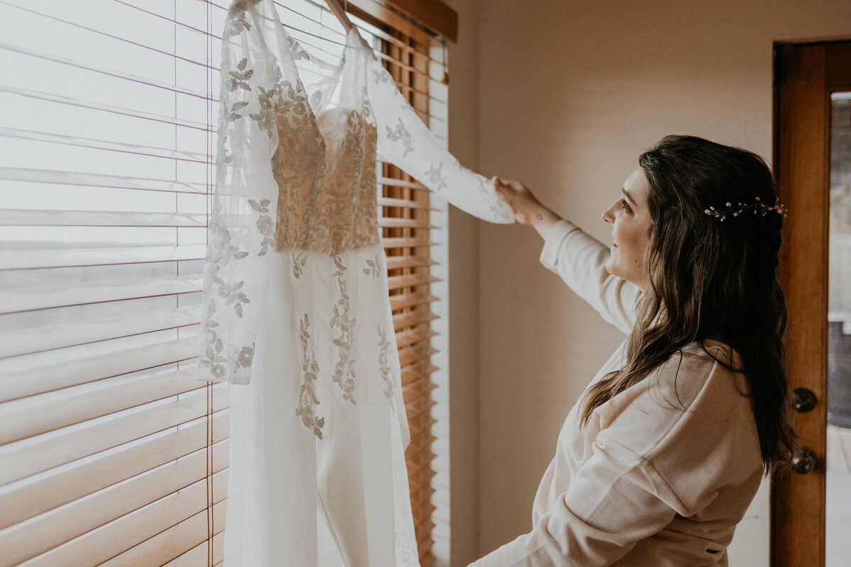 bride looking at her hanging lace jumpsuit before her ceremony