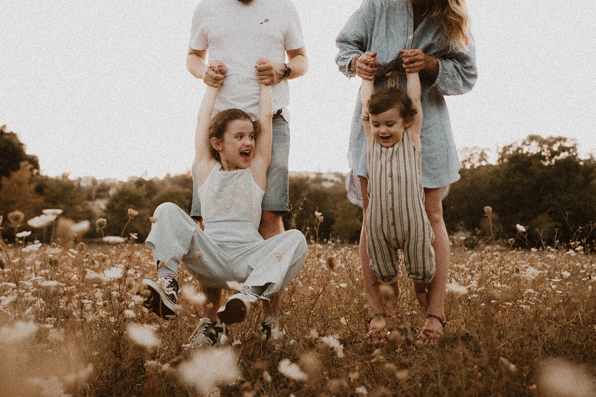 photo famille dans les champs  les enfants se suspendent aux bras de leurs parents