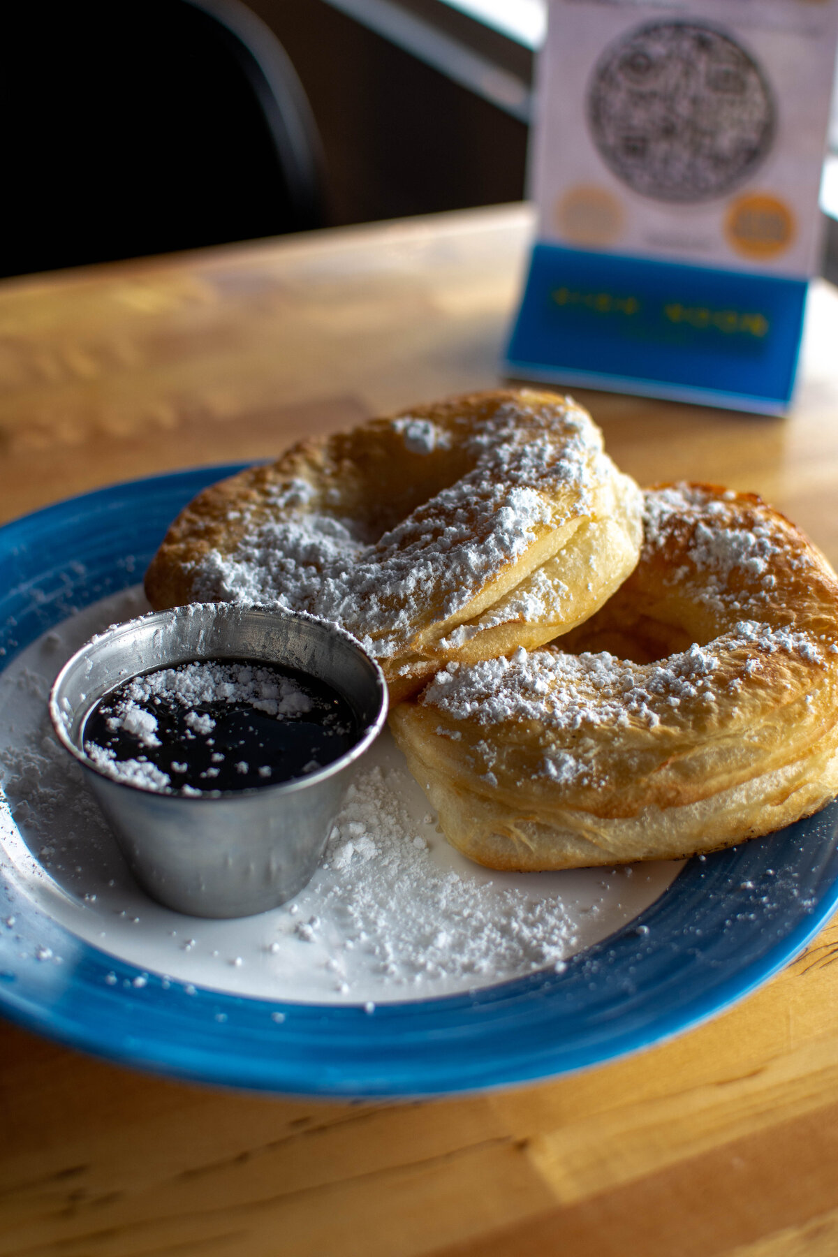 Two beignet donuts with syrup on a blue and white plate