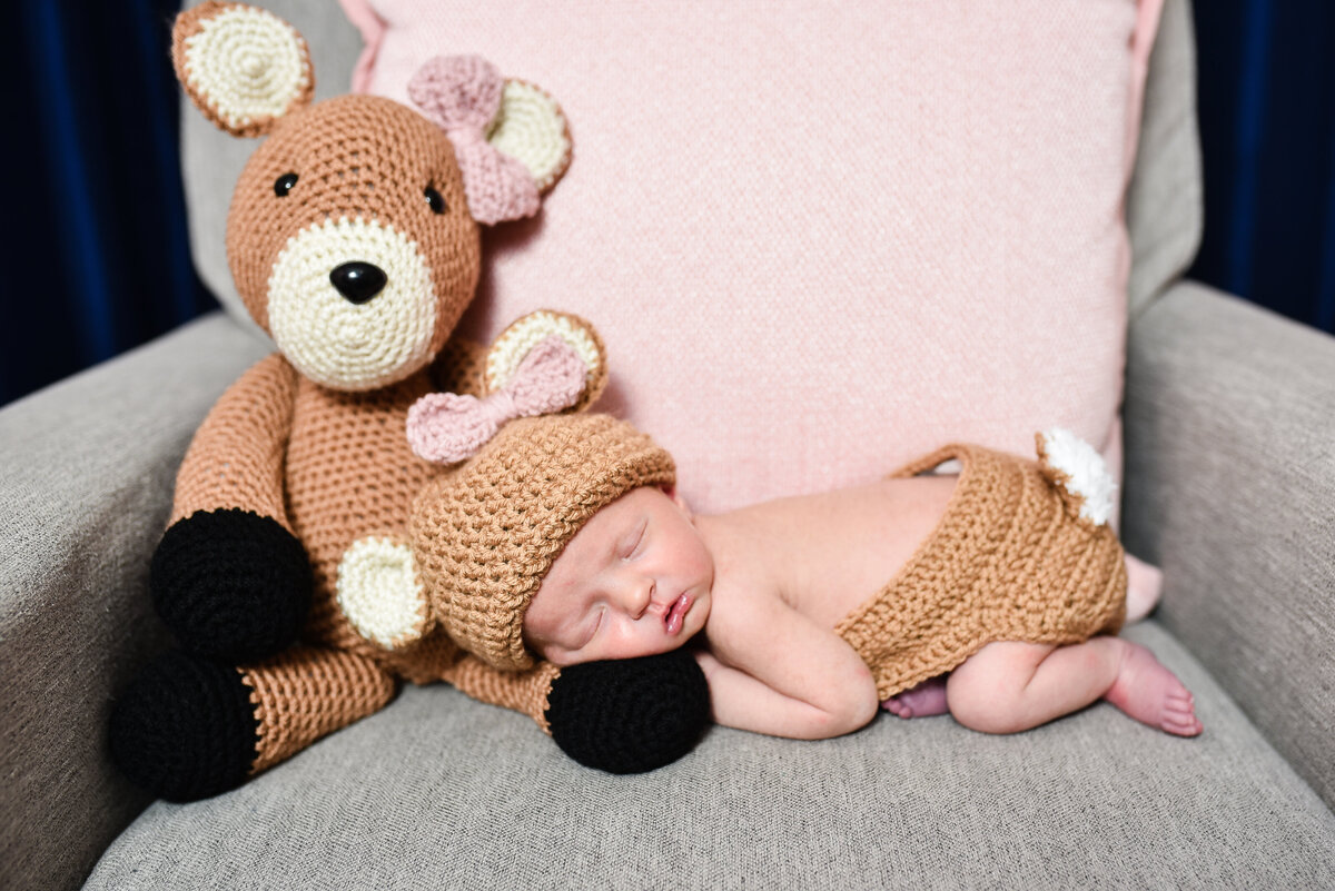 Beautiful lifestyle newborn photography: Baby girl with handmade deer and matching outfit in her nursery in Mississippi