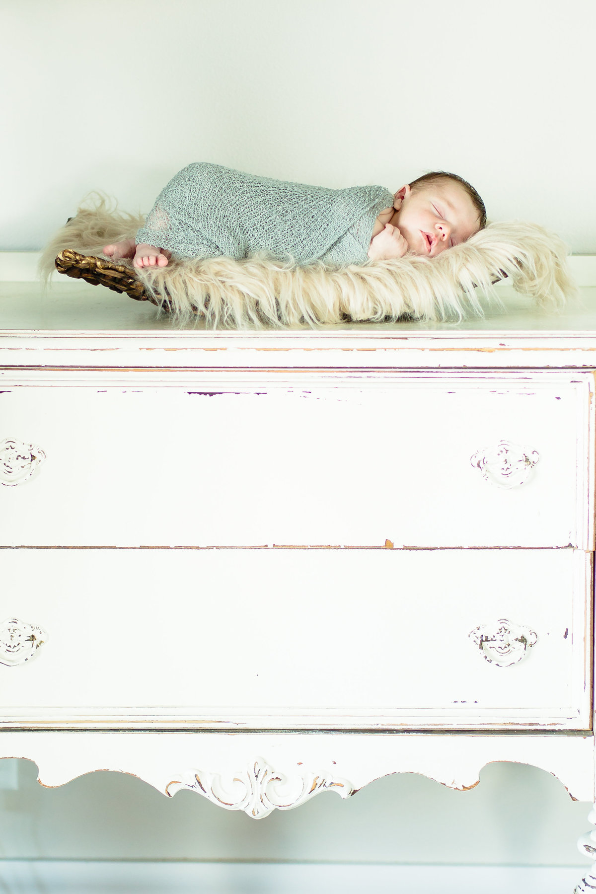 Newborn baby asleep on antique dresser