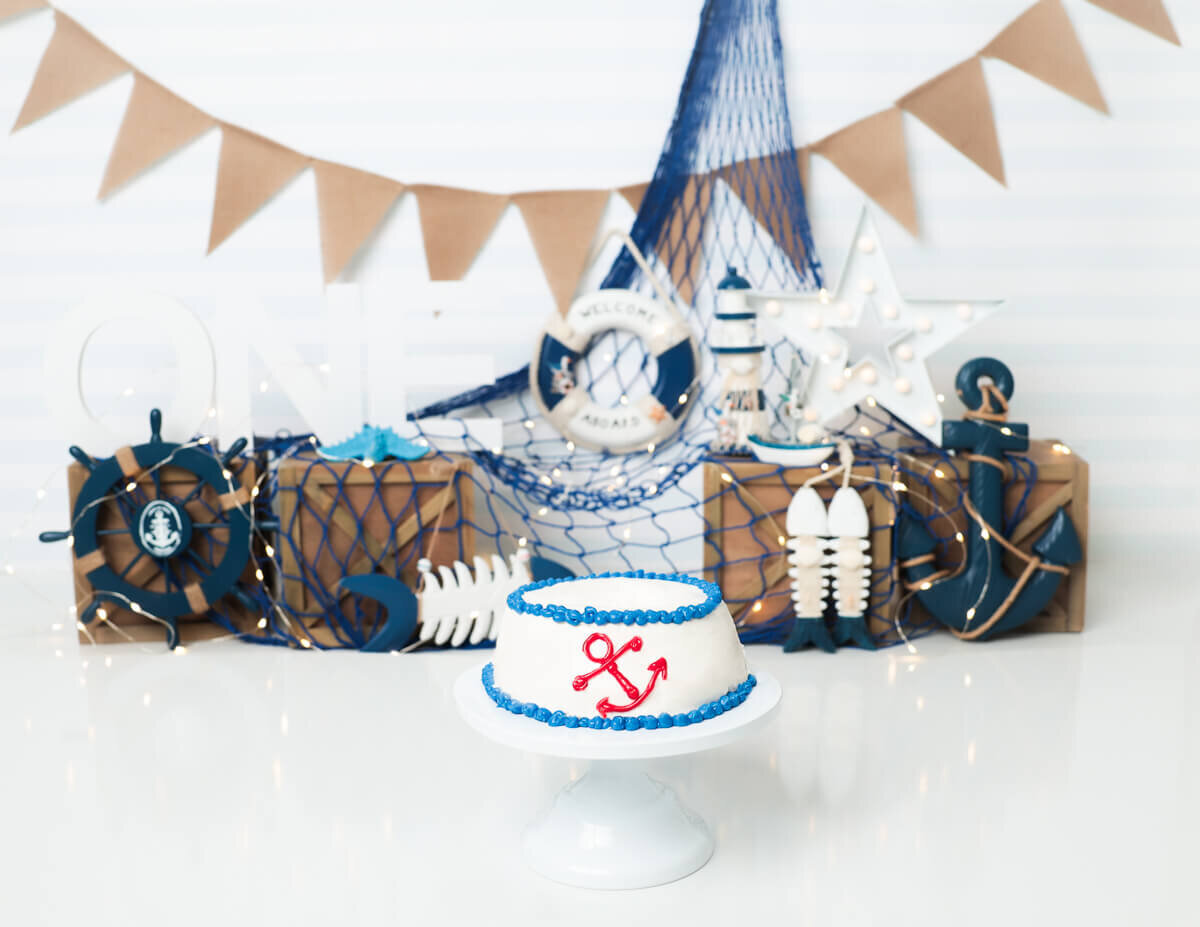Fun nautical birthday cake smash session in Rochester, NY, featuring blue and white decorations.