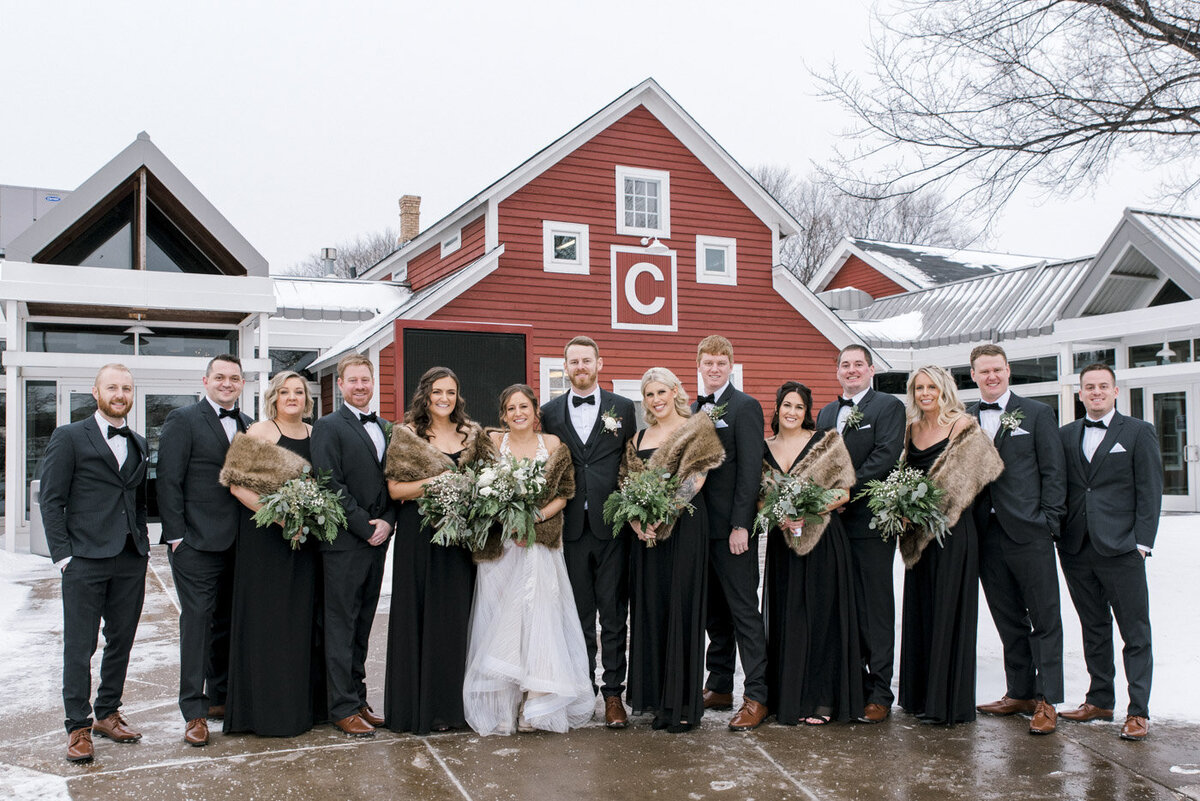 wedding party poses in front of barn