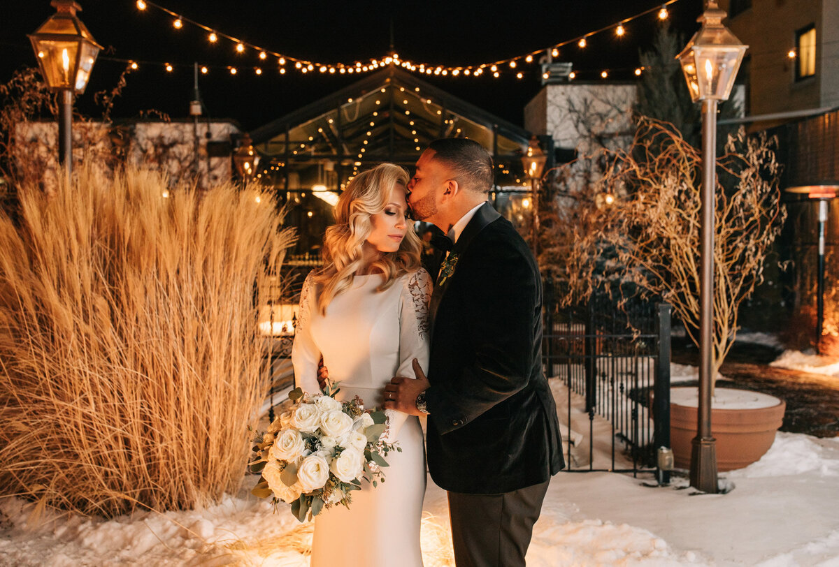 Groom kissing the bride on the forehead at their winter wedding