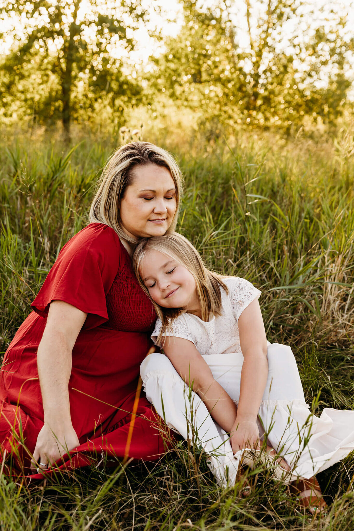 Mom in red dress snuggling & embracing daughter in a white dress in Milwaukee