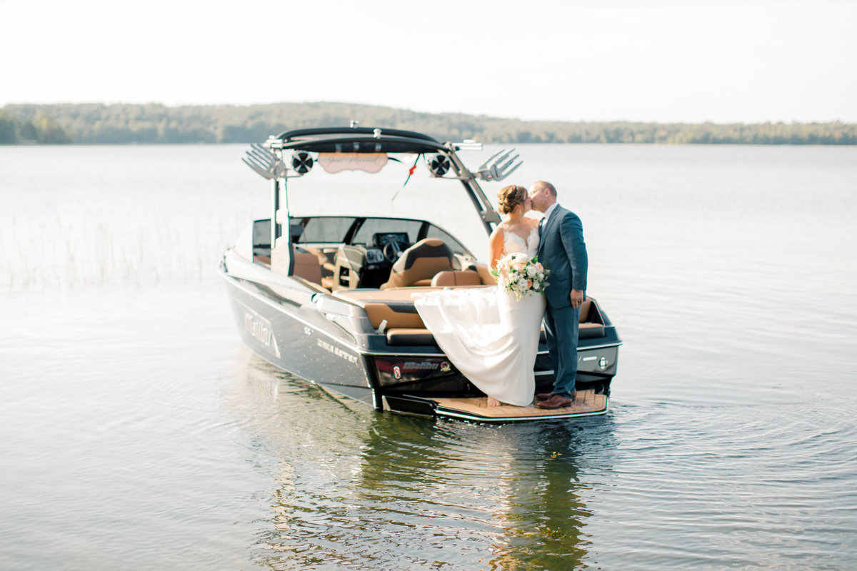 couple kisses on swim deck of malibu boat for lakeside intimate wedding brainerd minnesota