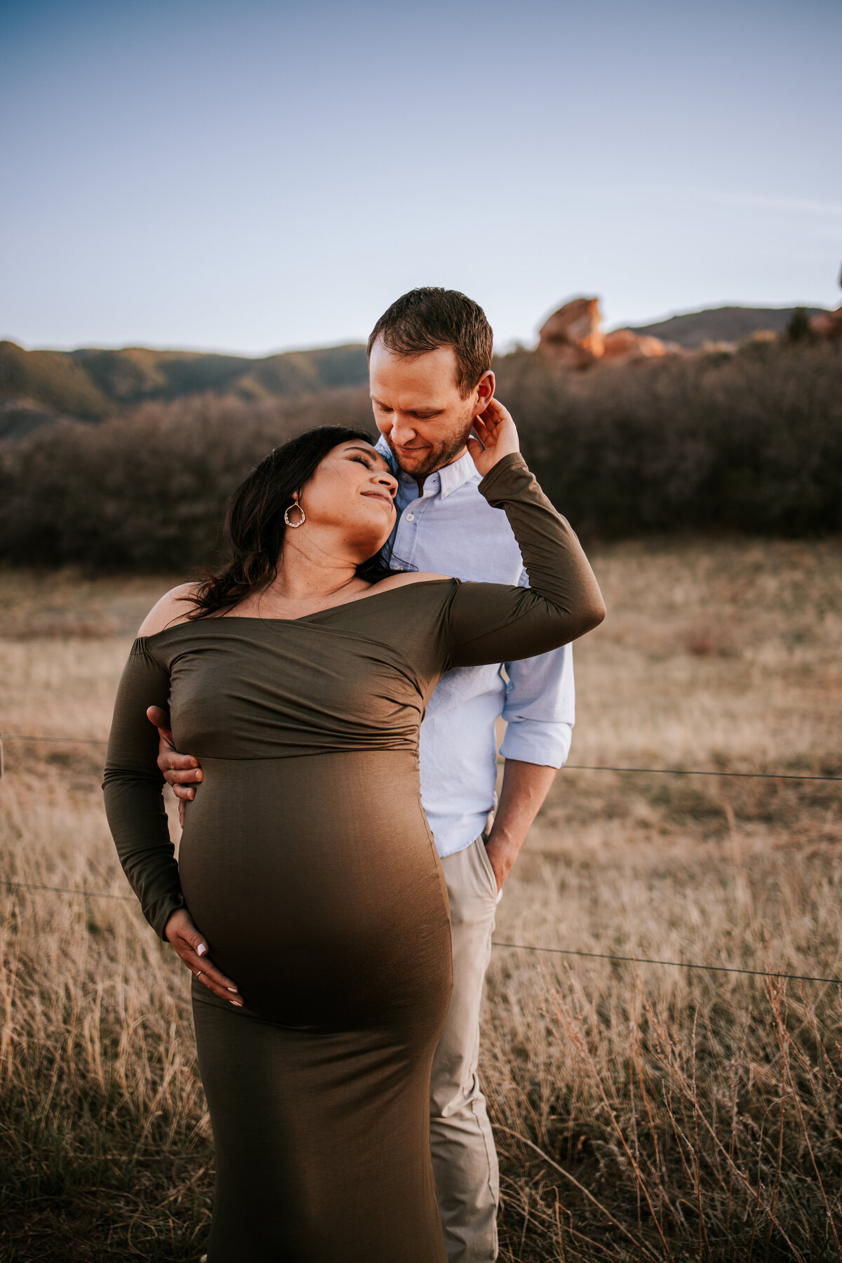 pregnant mom holds husband  during outdoor maternity session in denver