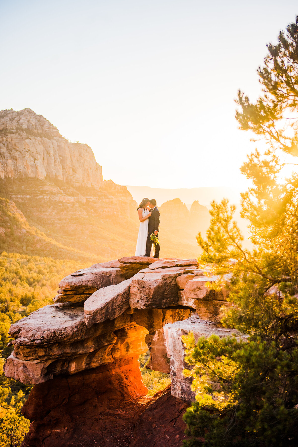 Bride and Groom standing on ledge at Merry Go Round Rock Sedona elopement sunset golden hour red rocks