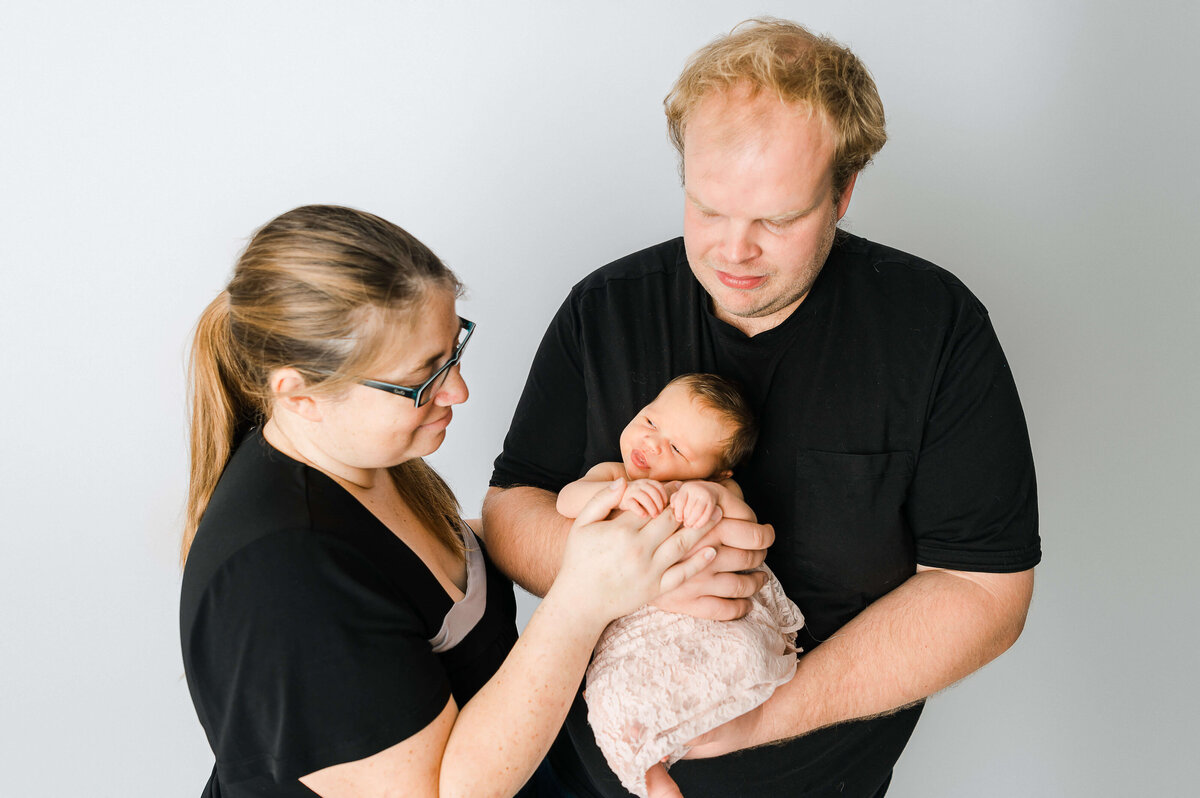 Edmonton new parents holding a newborn baby girl at a photography session with Cynthia Priest Photography