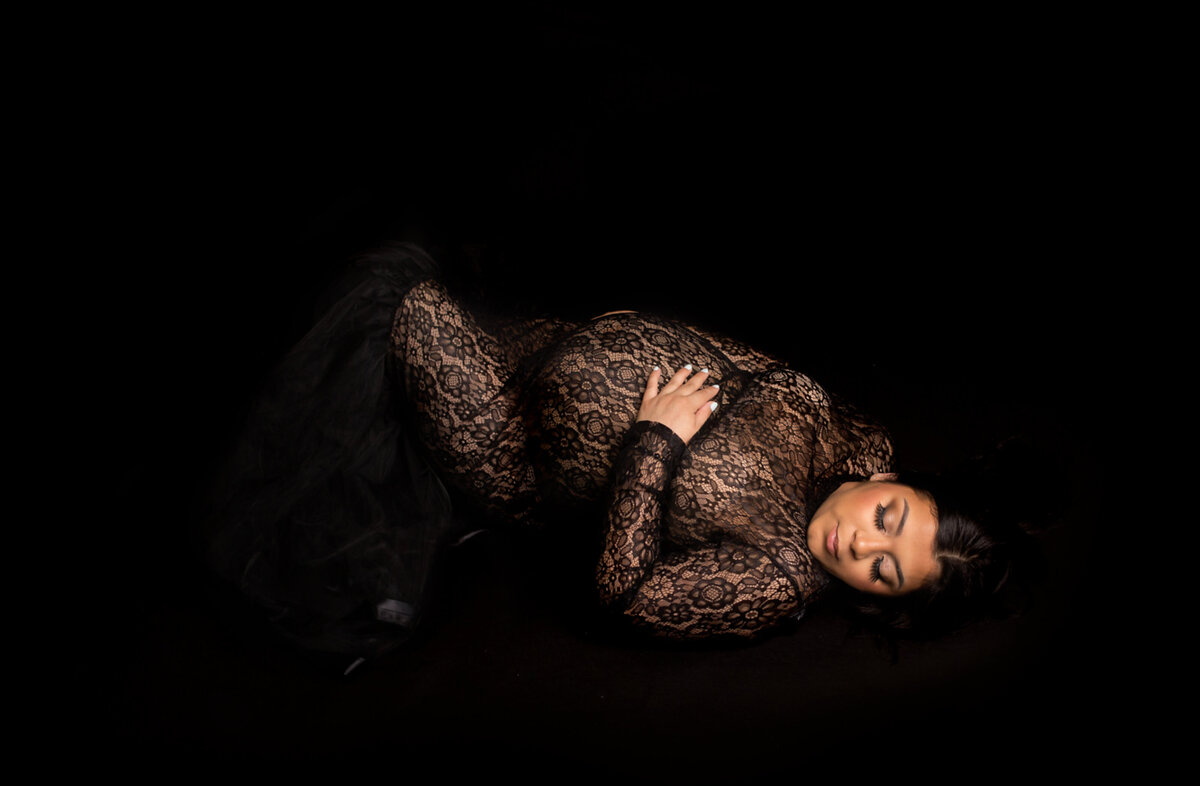 Women wearing black gown, laying down during maternity photoshoot in Mount Juliet Tennessee Photography studio