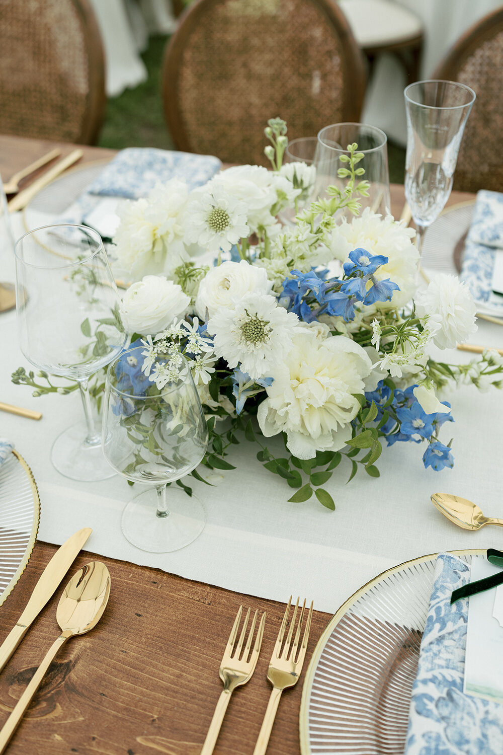Blue and white floral centerpiece featuring hydrangeas, roses, and delphiniums arranged in a delicate vase for a French blue summer wedding in Jackson, WY.