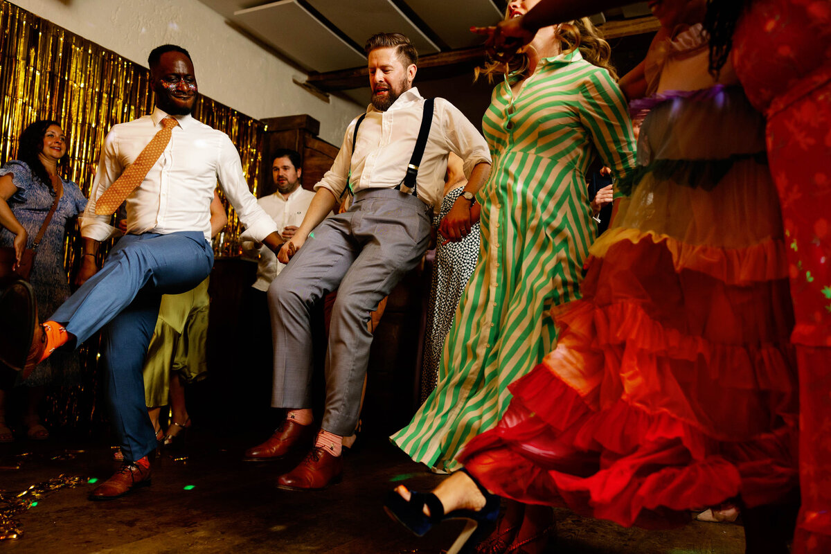 Groom in mid air dancing with his friends