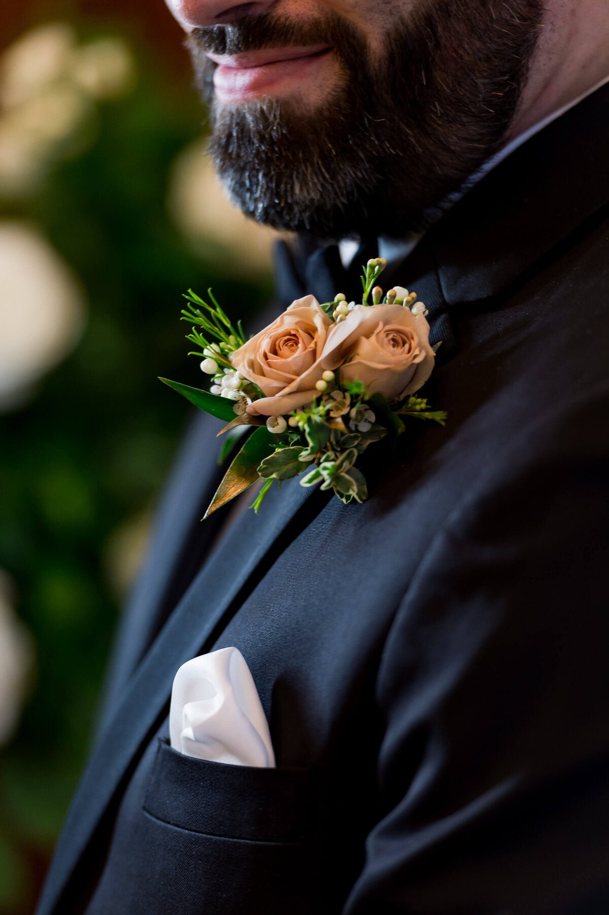 a closeup photo of a blush rose boutonniere on a groom's black tuxedo photographed during an Ottawa wedding at the Chateau Laurier hotel