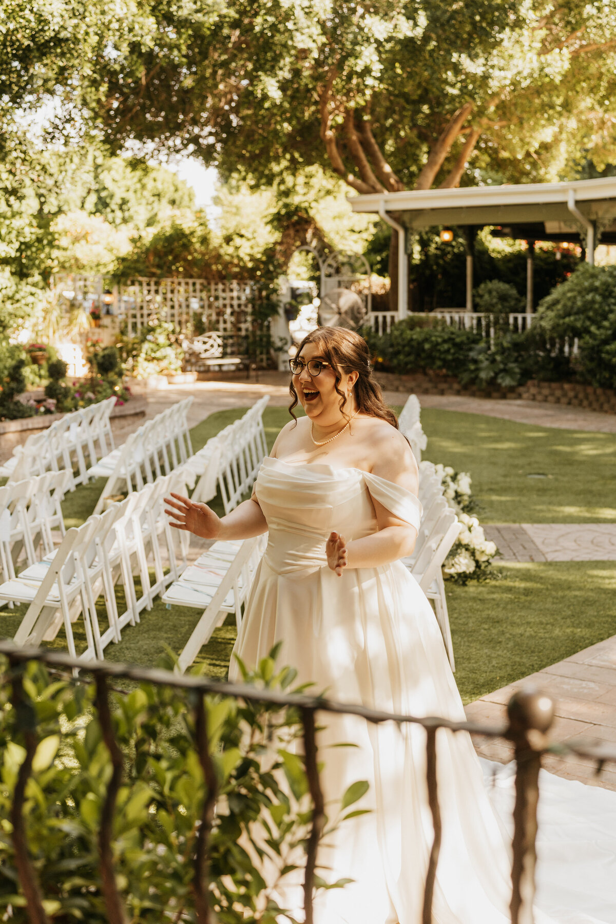 A person in a wedding dress with their hands out smiling in surprise 