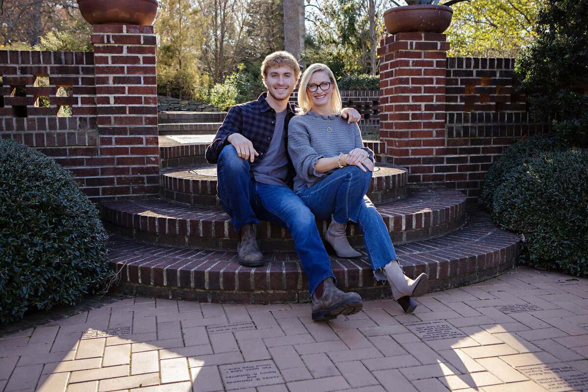Tender fall moment of mom and son on brick steps surrounded by colorful foliage at UNCC Botanical Garden