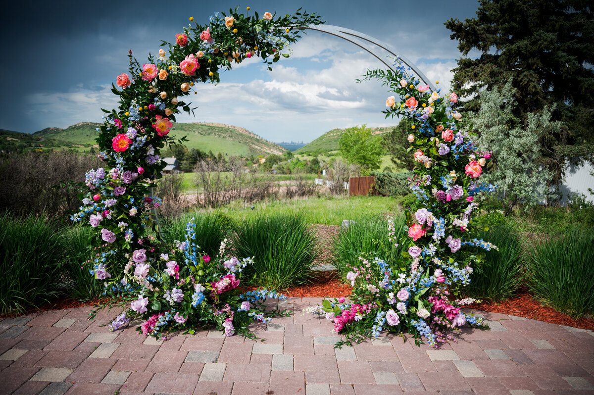 A wedding circle arch is adorned with spring flowers for a wedding ceremony at The Manor House in Littleton, Colorado.