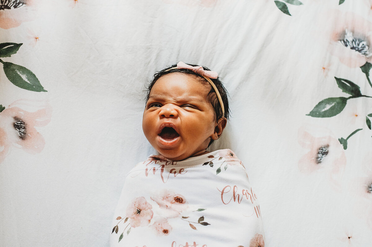 newborn photos with baby girl in a floral swaddle yawning captured by Family photographers Maryland