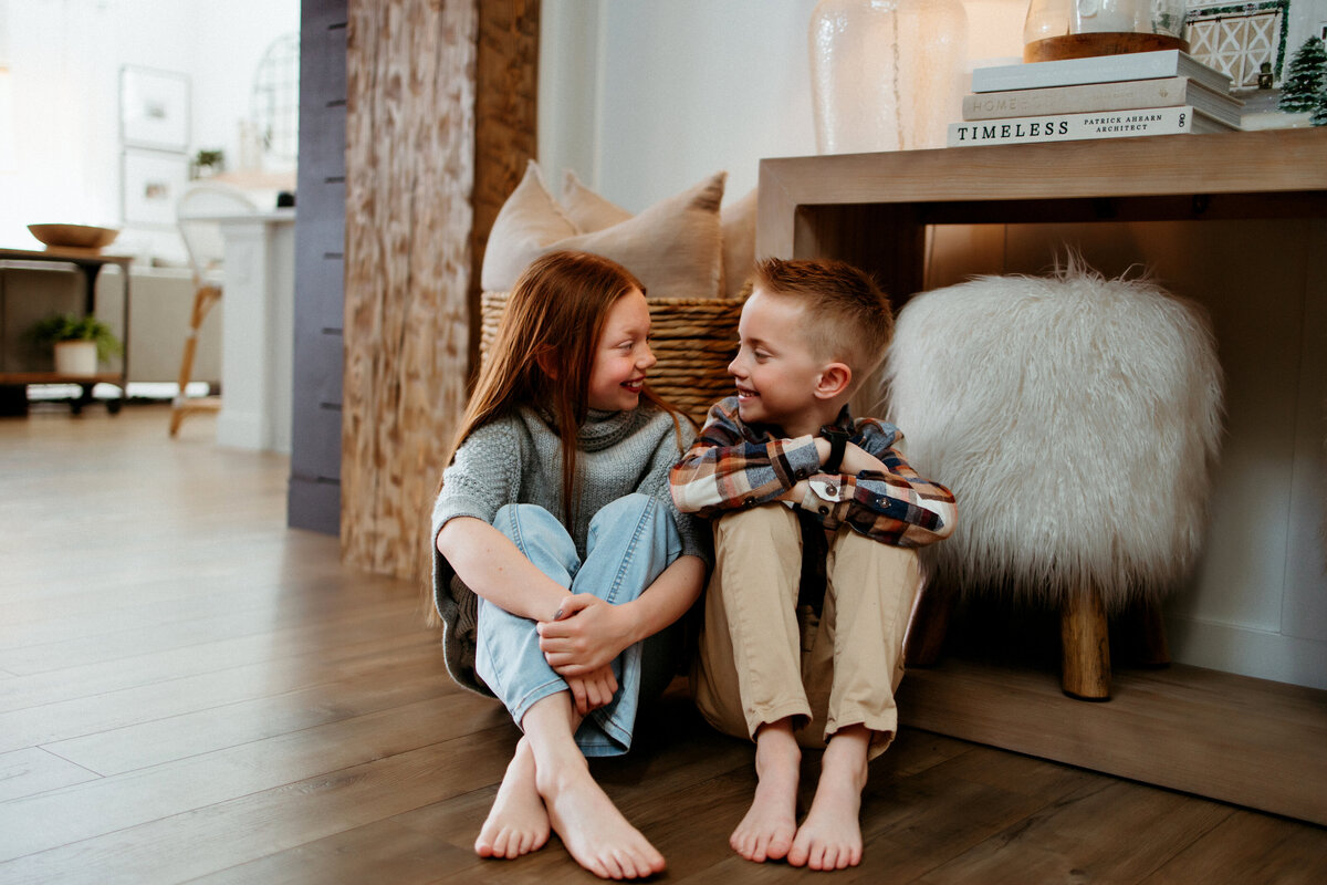 two kids sit together on wooden floor