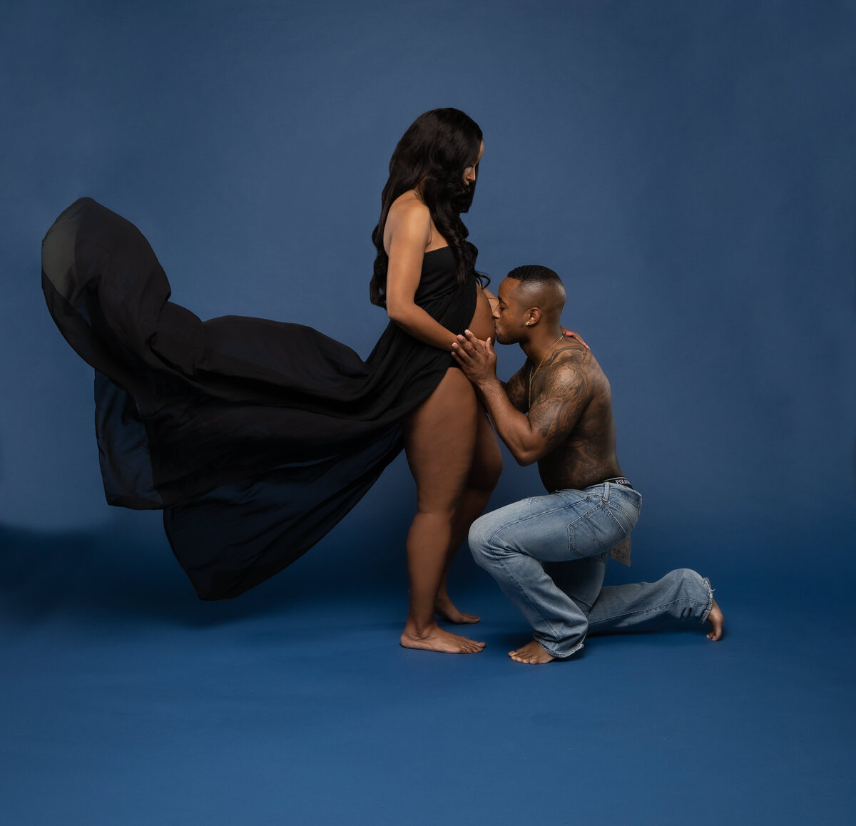Black couple in blue jeans posing for maternity