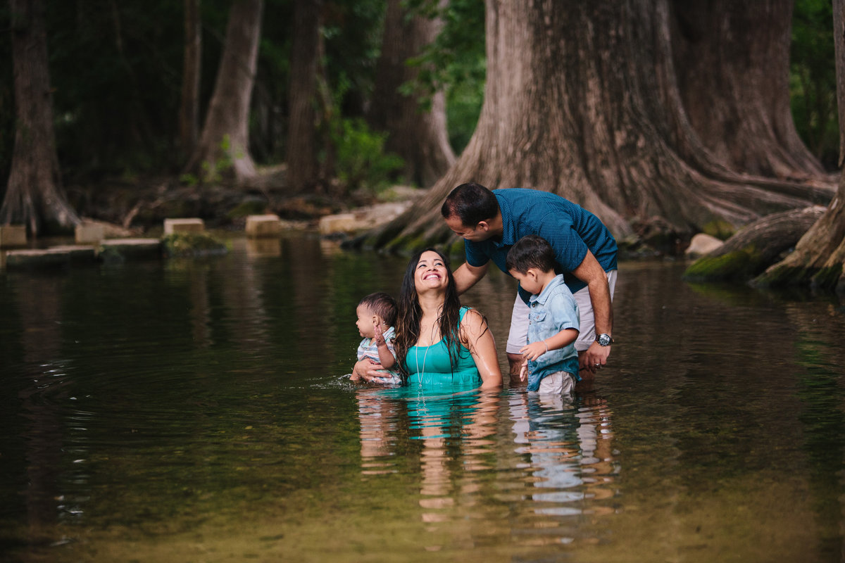family portrait of couple sitting in river playin with their children by San Antonio photographer