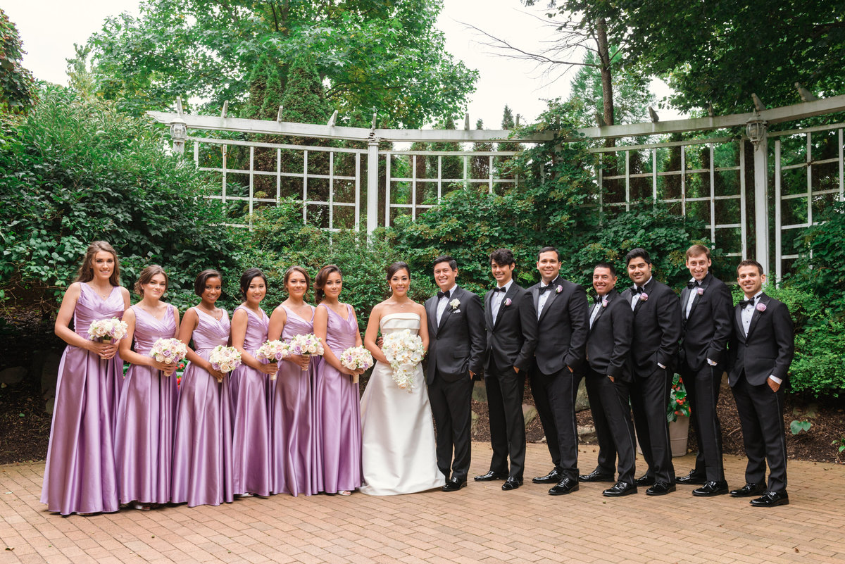 photo of bride and groom with entire bridal party in the outdoors garden at The Garden City Hotel