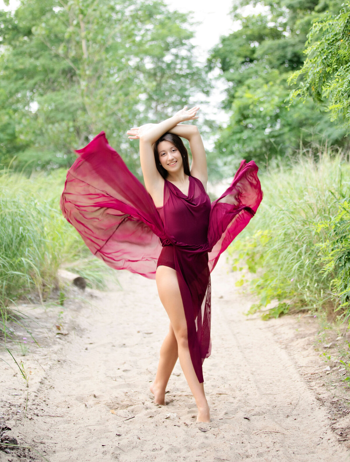 Senior photo of a dancer throwing her dress on a sandy path at Presque Isle State Park in Erie pa