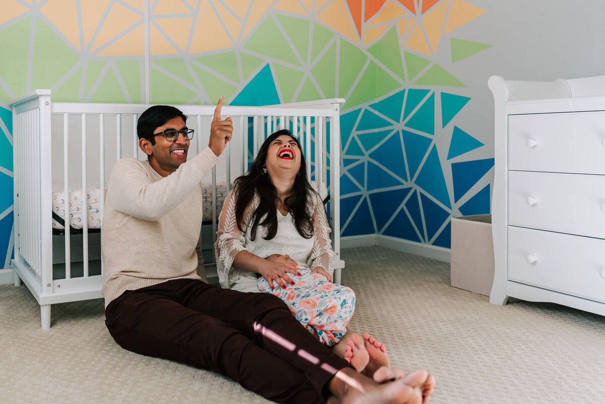 new parents laughing about baby sleep behaviors during their newborn photography by Denise Van