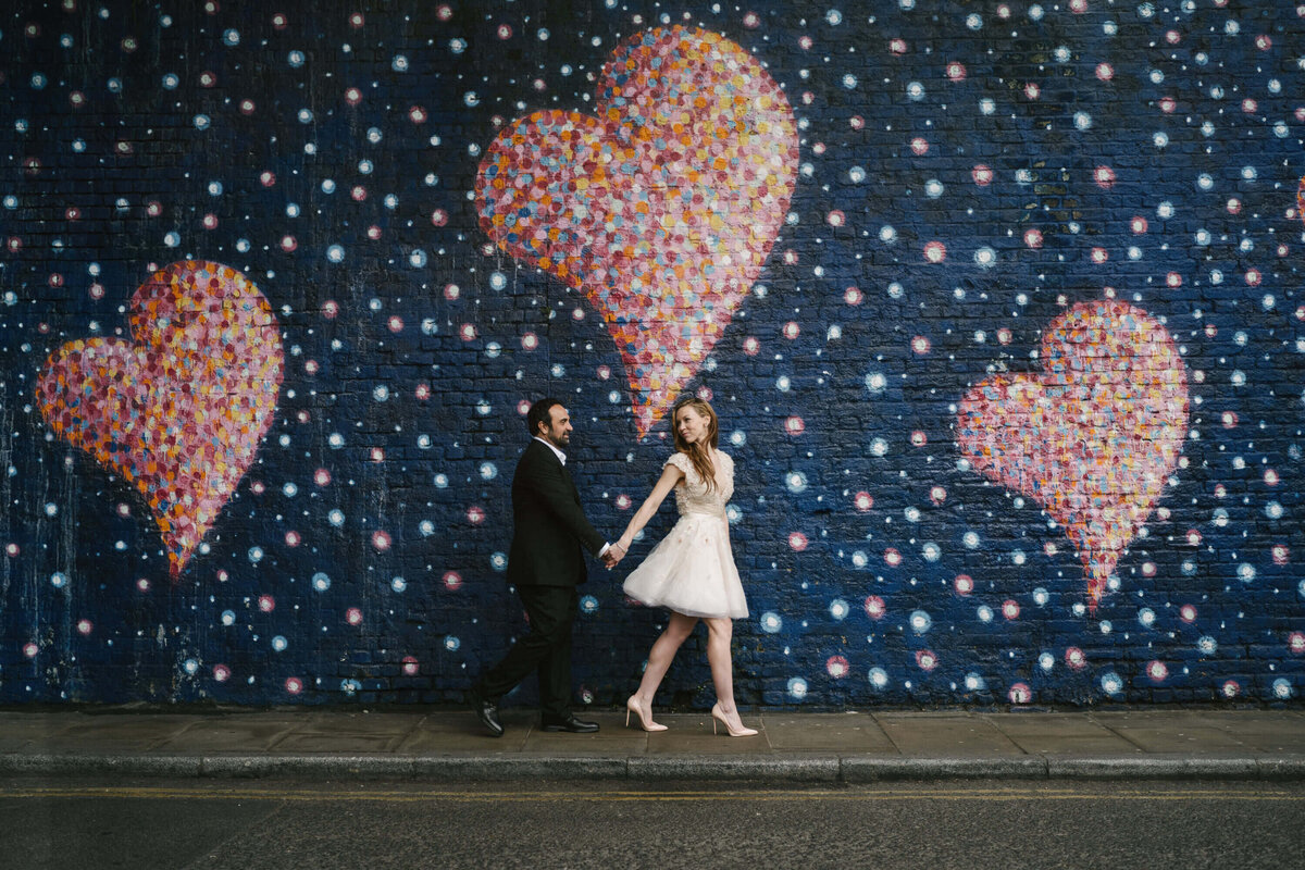 A bride and groom walking past some streetart