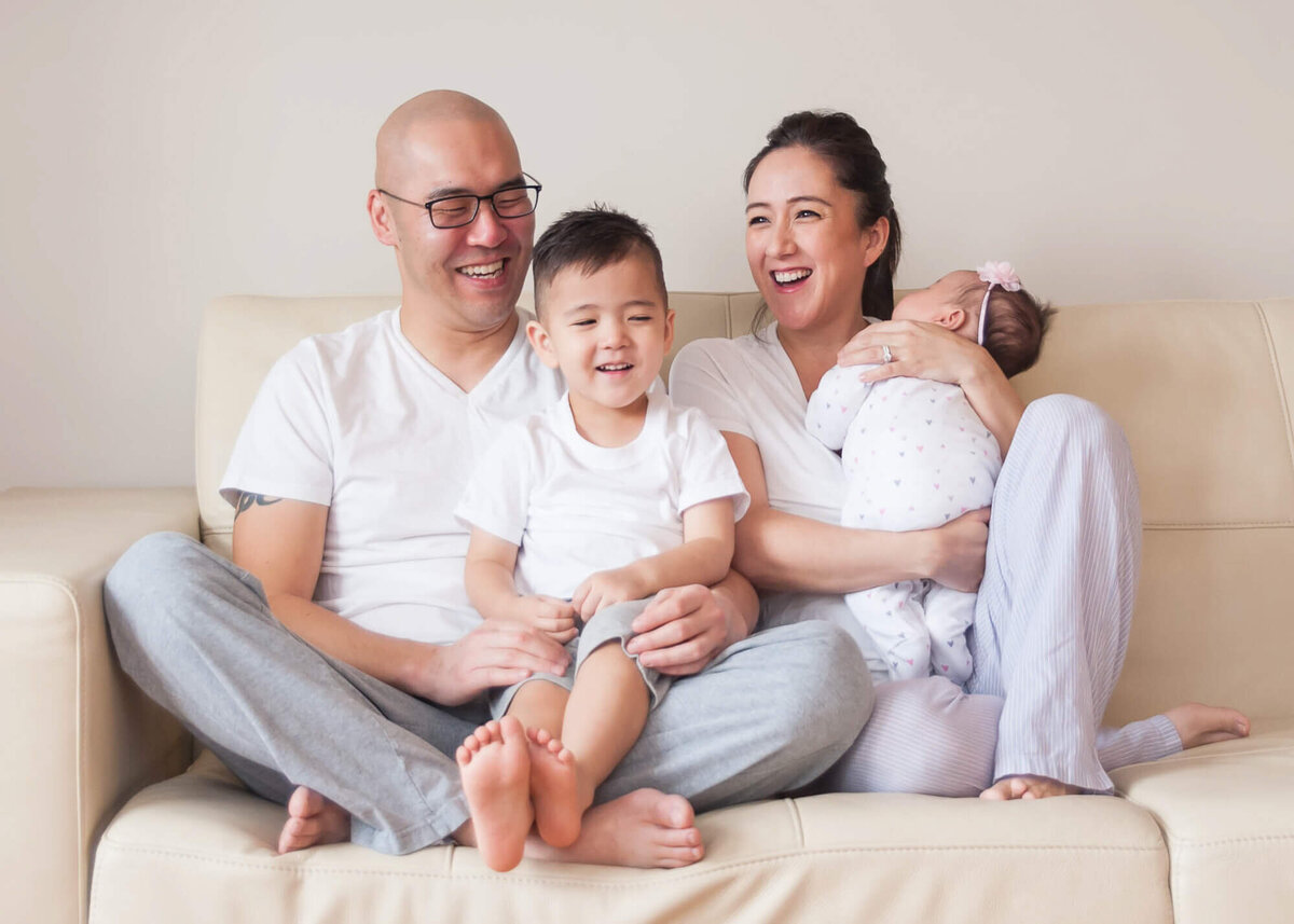 Lifestyle family newborn session in home family laughing together on sofa